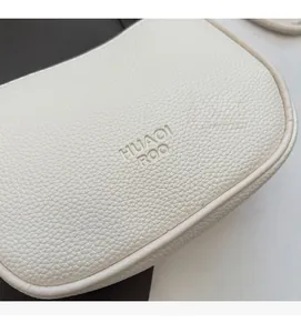 Close-up of beige lychee grain leather with embossed HUAOI ROO logo and clean stitching