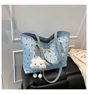 Detail of light blue quilted tote bag with rabbit print, gold bow, and cloud charm