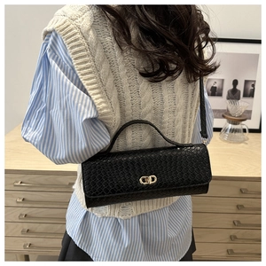 Detail of black woven texture square bag with gold metal clasp on model shoulder