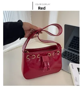 Detail of red patent leather handbag featuring gold rings and decorative drawstrings