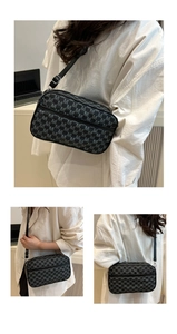 Detail view of a black crossbody camera bag with all-over M-letter print and zippers