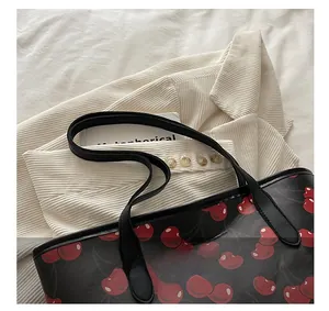 Detail of black tote bag with cherry print, leather handles and stylish casual texture