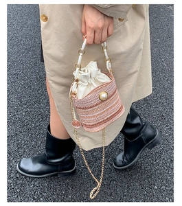 Détail du sac seau tissé avec rayures roses, perle décorative et poignée en résine