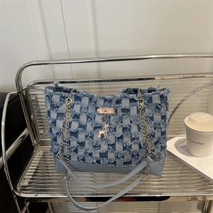 Sac cabas en jean bleu avec motif damier et franges sur un support argenté