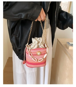 Dettaglio borsa a secchiello rosa intrecciata con perla grande e catena mista