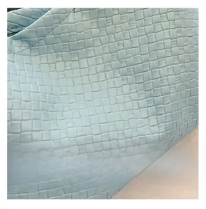 Close-up of the light blue woven leather texture on a minimalist shoulder bag design