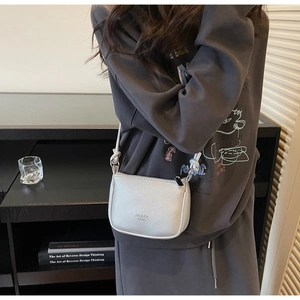 Close-up of silver lychee pattern crossbody bag with brand logo and zipper detail