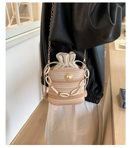 Détail d'un sac seau en paille tressée avec boucle en perle et chaîne blanc mat