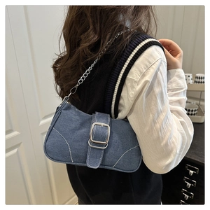 Close-up of denim underarm bag with large silver buckle and chain shoulder strap