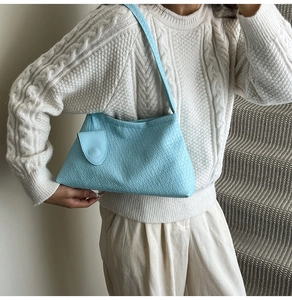 Close-up of light blue woven texture shoulder bag with a small decorative front pocket