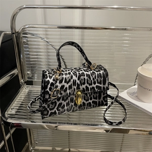 Stylish black and white leopard print crossbody bag with gold buckle and top handle