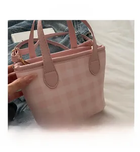 Detail of pink checkered crossbody bag showing gold metal buckle and leather texture