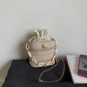 Straw bucket bag with striped weave, large pearl accent, and white acrylic chain handle