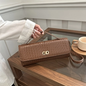 Brown woven texture rectangle handbag with golden CD metal lock on a wooden cafe table