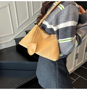 Detail of tan woven bucket bag featuring unique knotted shoulder strap and matching charm