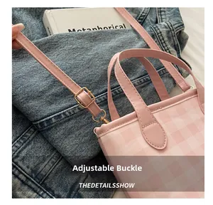 Close-up of pink checkered handbag with adjustable gold metal buckle on leather strap