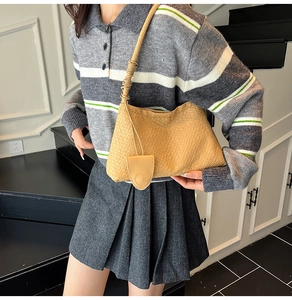 Detail der beigen geflochtenen Hobo-Tasche kombiniert mit grauem Strickpullover und Rock