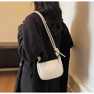 Detail of creamy white litchi textured leather underarm bag with stylish strap knots