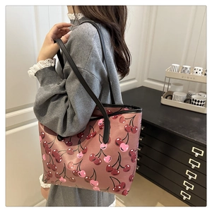 Detail of large tote bag featuring vintage pink finish and dense cherry print pattern