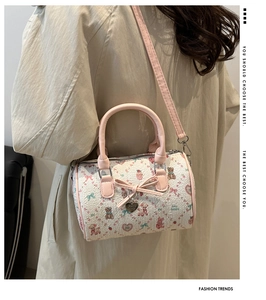Détail du sac polochon rose et blanc avec imprimés cartoon et nœud de décoration
