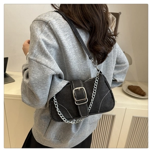 Detail der schwarzen Denim-Schultertasche mit weißen Nähten und silberner Kette