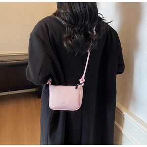 Pink litchi texture mini saddle bag with HUAOI ROO logo shown on a black coat