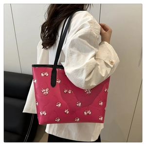 Detailed back view of pink tote bag with cherry print on model with black shoulder straps
