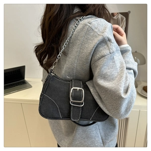 Detail of black denim shoulder bag with white contrast stitching and silver buckle