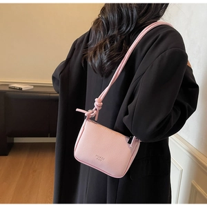 Detail of pink lychee leather mini crossbody bag featuring a knotted strap design