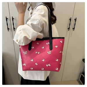 Detail of pink cherry print tote bag featuring black leather straps and large capacity