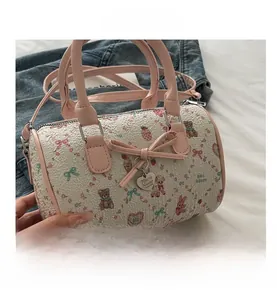 Gros plan détaillé du sac Boston blanc à fleurs avec pendentif cœur rose et nœud