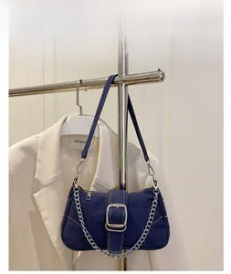 Detailaufnahme der blauen Denim-Baguette-Tasche mit silberner Schnalle und Kettenelementen