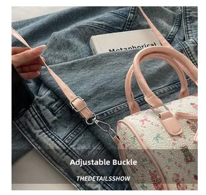 Détail de la boucle réglable en métal et de la bandoulière rose sur un sac Boston