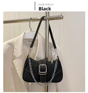 Details einer schwarzen Denim-Schultertasche mit silberner Kette und großer Schnalle am Ständer