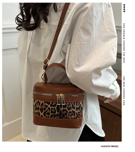 Detailed side view of leopard print bucket bag with brown leather contrast and gold zipper