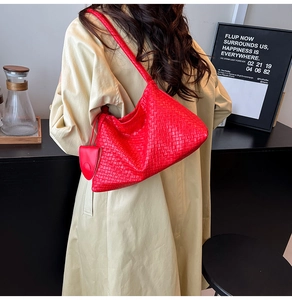 Detail der roten handgewebten Leder-Hobo-Tasche mit Anhänger an Model im beigen Mantel