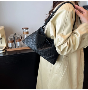 Detail of woven leather black shoulder bag with a knotted strap and chic textured finish