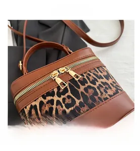 Detail of caramel leather cylinder bag with leopard print panel and golden zipper closure