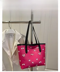 Detail of fuchsia tote bag with red cherry pattern and black faux leather straps