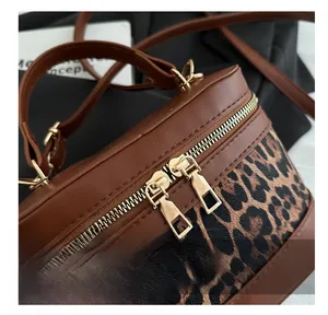 Detail of smooth gold dual zipper and leopard print fabric on brown bucket bag