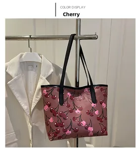 Detail of dust-pink tote bag with red cherry print and black leather straps
