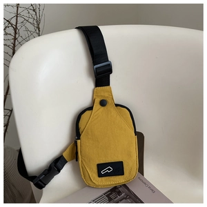 Detail of a bright yellow waterproof nylon sling bag with a black logo patch and buckle strap