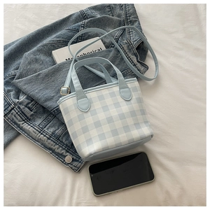 Detail of blue and white checkered tote bag showing adjustable leather strap and texture