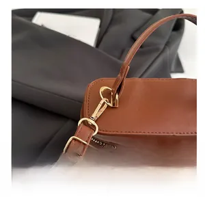 Detail of gold metal hooks, dual-way zippers, and leopard print on a brown bucket bag