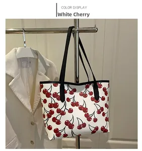 White cherry print tote bag with black leather straps hanging on a metal hanger