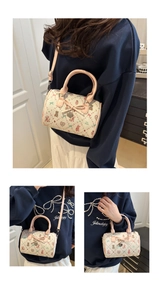 Détail du sac Boston crème avec imprimé ours fraise et poignée en cuir rose