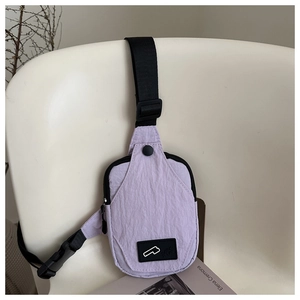 Detail of lavender nylon sling bag with texture, adjustable strap on a white chair