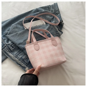 Detail of pink plaid mini tote bag with adjustable shoulder strap on soft white linens