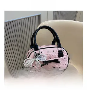 Pink pleated bag with black bow details and pearl lace charm on a white chair