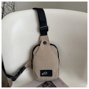 Detail of a beige nylon crossbody bag hanging on a chair with black straps and buckle